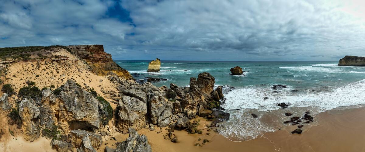 A coastal landscape with rocky cliffs, sandy beach, and the ocean.