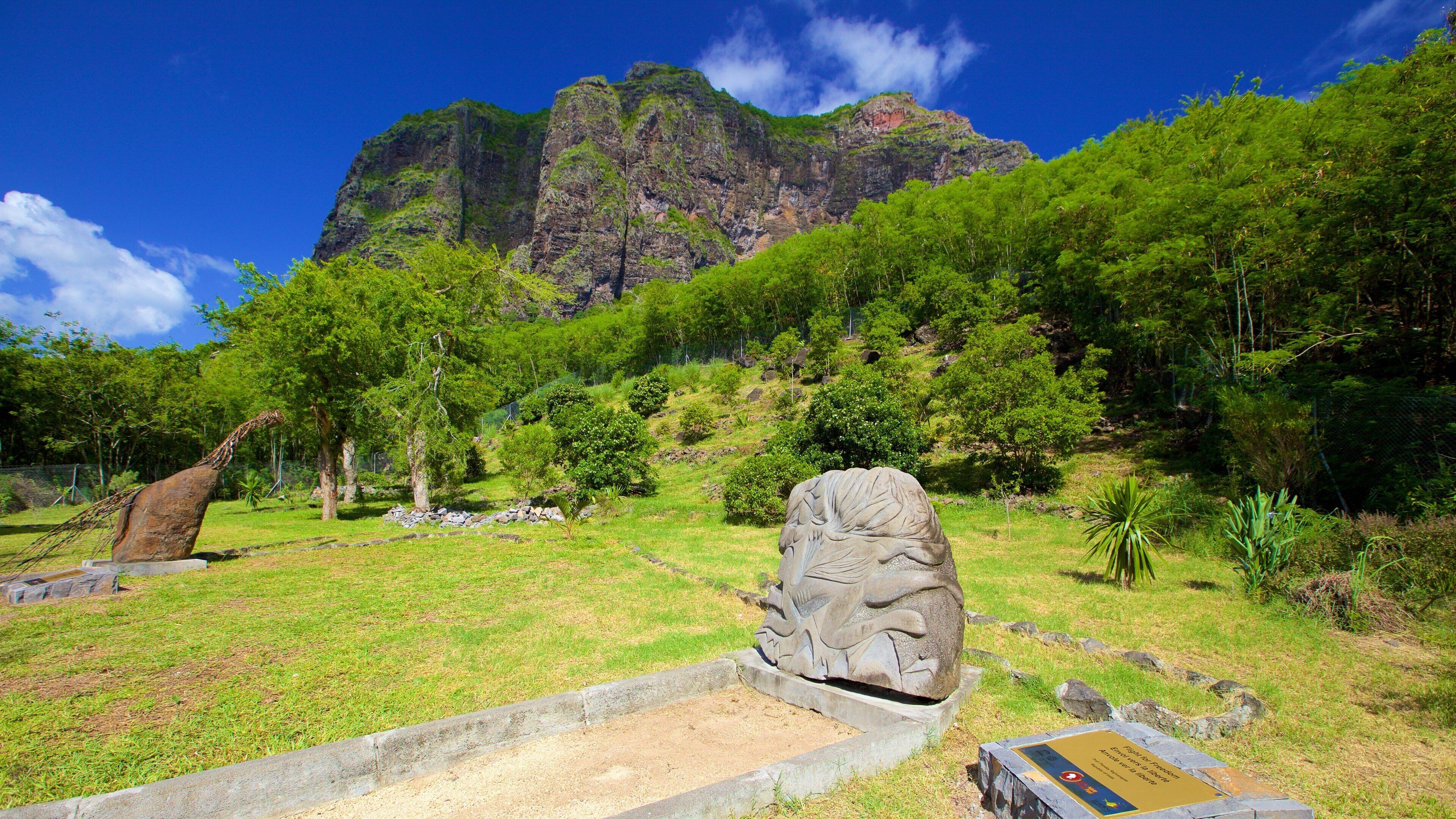 A stone sculpture in a grassy area with a mountain in the background.