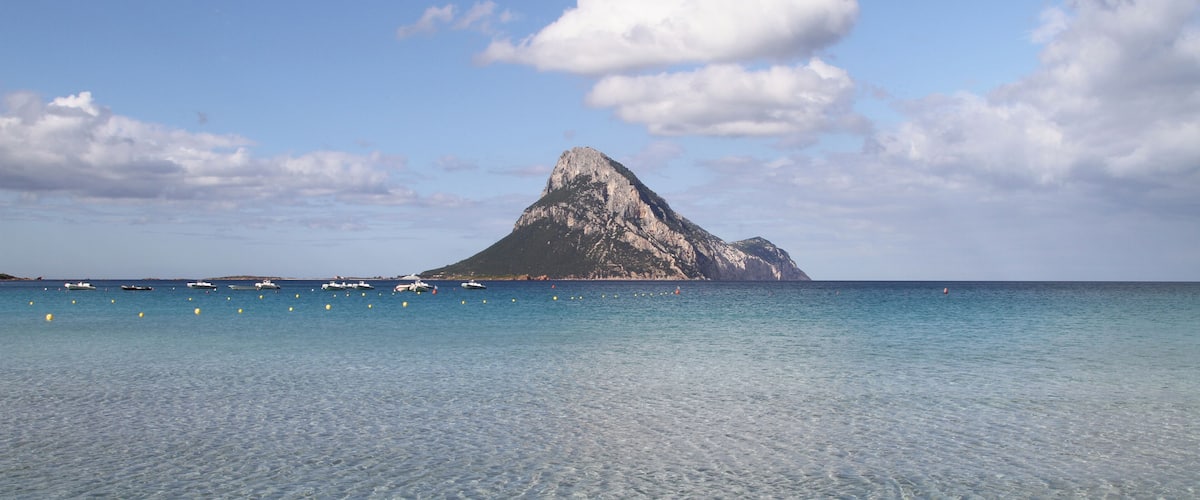 A clear blue sea with a rocky island in the distance.