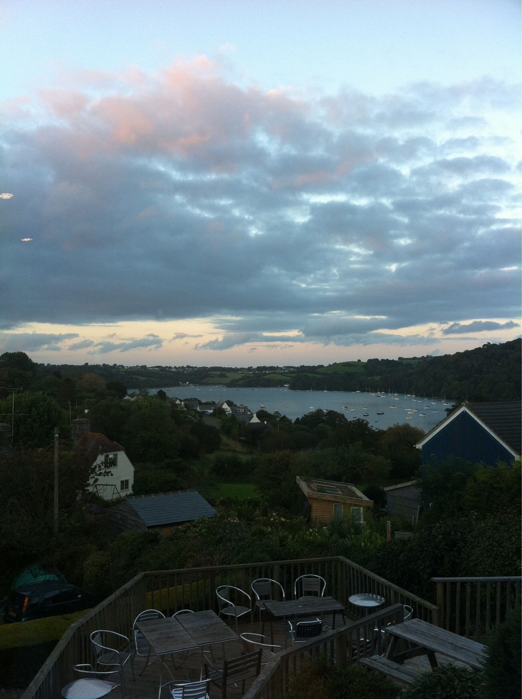 A coastal landscape with a view of a bay, boats, and houses.