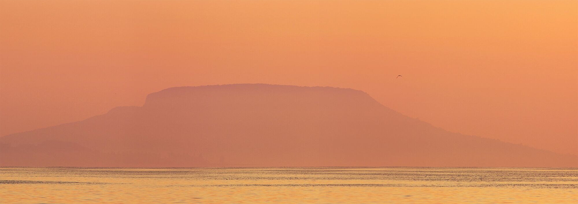 A mountain silhouette against a sunset sky.
