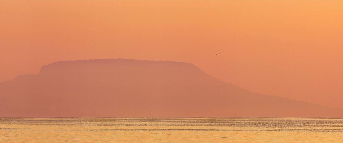 A mountain silhouette against a sunset sky.