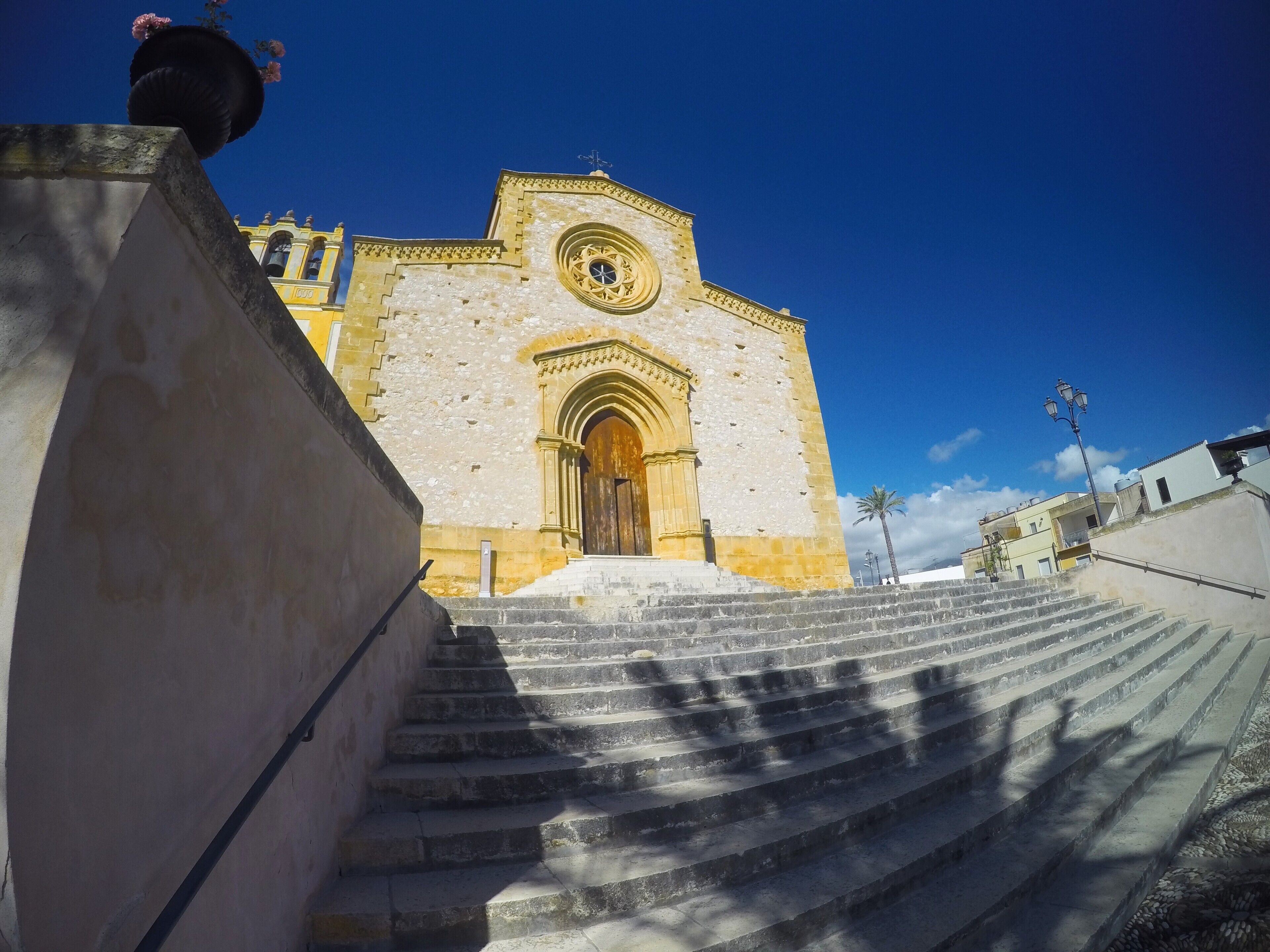 A stone staircase leading to a historic building with a large circular window and an arched entrance.