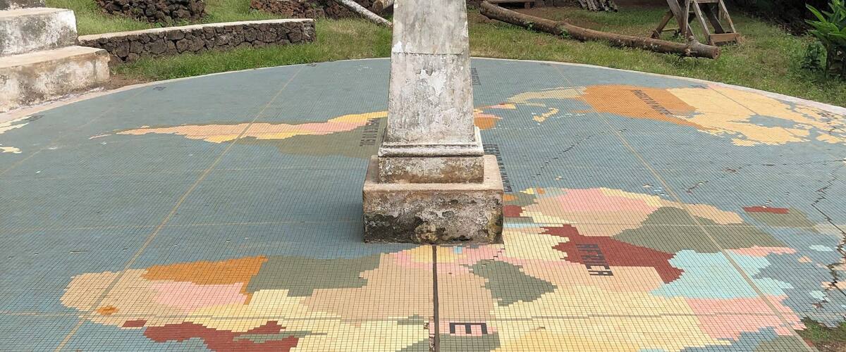 A tiled floor with a central column and a globe on top.