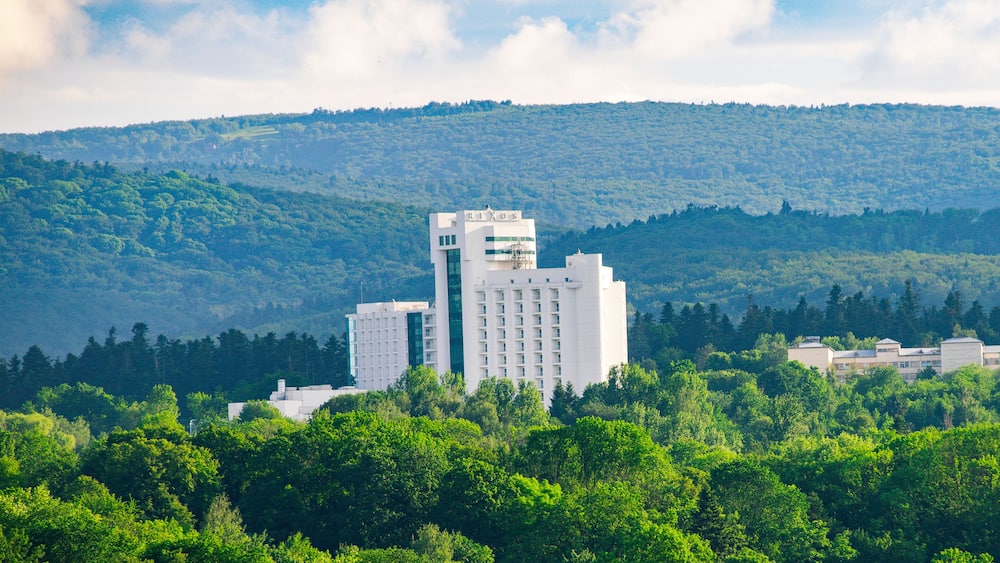 A hotel named RIXOS surrounded by lush green trees and hills.