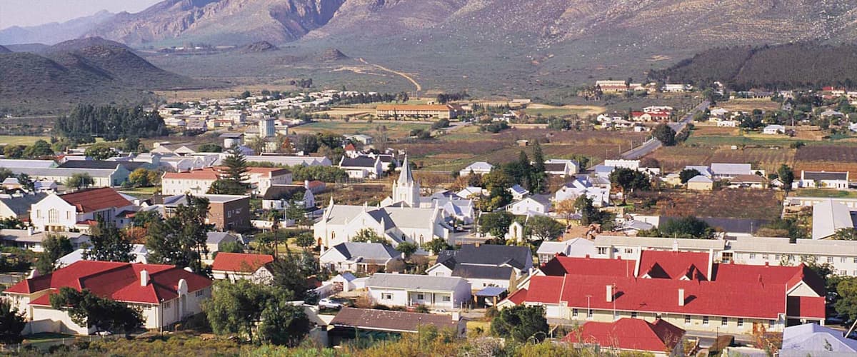 A town nestled in a valley with mountains in the background.