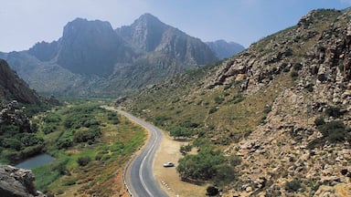 A winding mountain road flanked by rocky terrain and sparse vegetation.