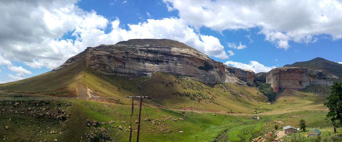 A mountainous landscape with a prominent peak, a valley, and a small building.