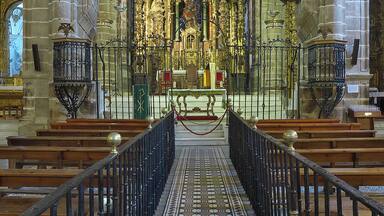 An ornate church interior with a central altar, pews, and intricate ceiling artwork.