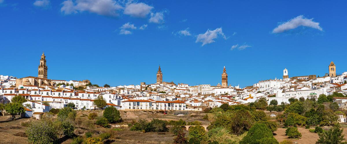 Un borgo costiero con edifici bianchi, un'imponente torre campanaria e vista sul mare.