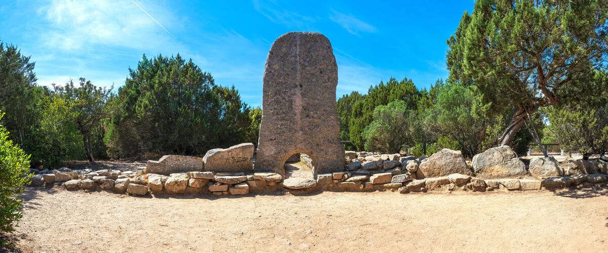 A stone monument surrounded by rocks and trees.