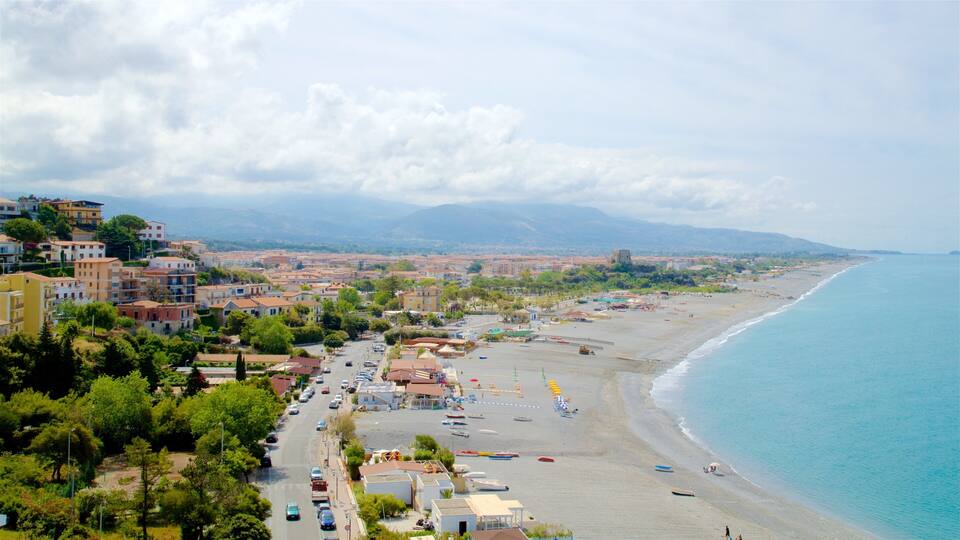 A coastal town with a beach, buildings, and mountains in the background.