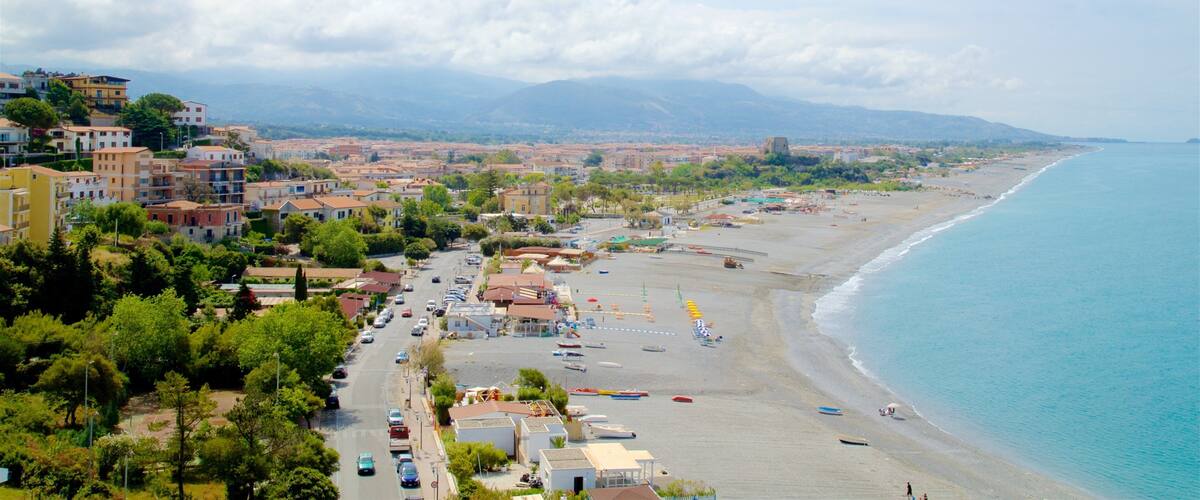 A coastal town with a beach, buildings, and mountains in the background.