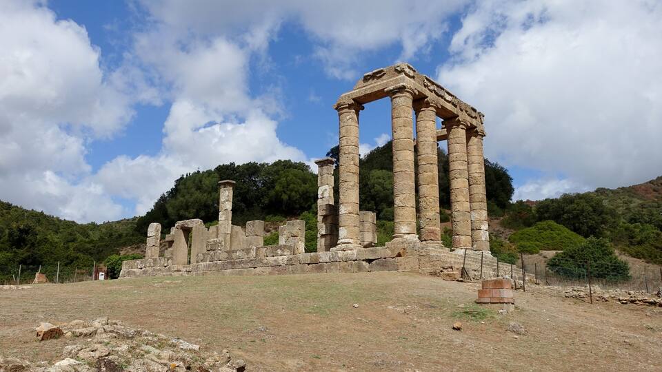 Ancient ruins with columns and stone structures on a hillside.