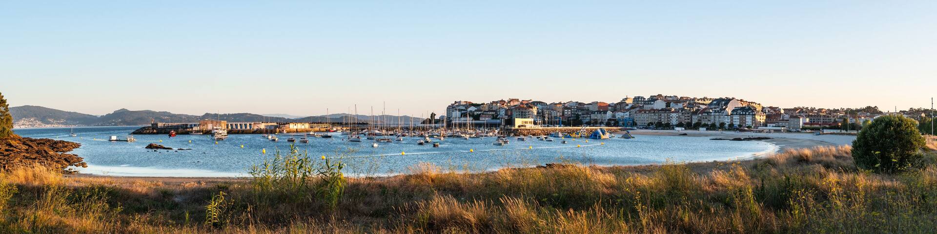 A coastal town with boats on the water, a beach, and buildings in the background.