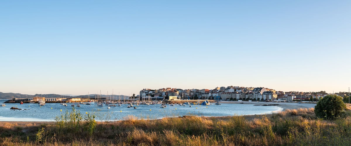 A coastal town with boats on the water, a beach, and buildings in the background.