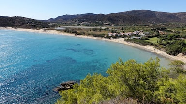A coastal landscape with a clear blue sea, sandy beaches, and a backdrop of hills.