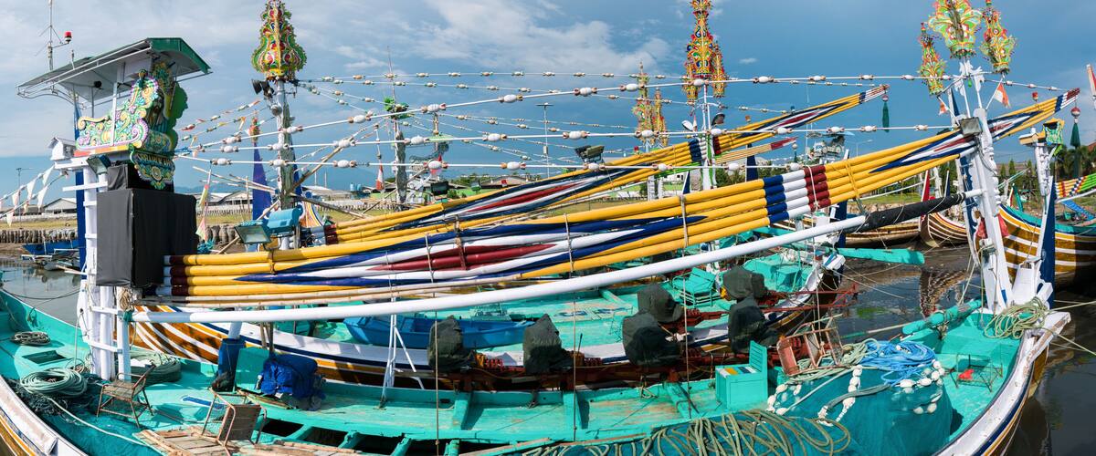 A traditional boat with colorful canopies and ropes, docked at a pier.