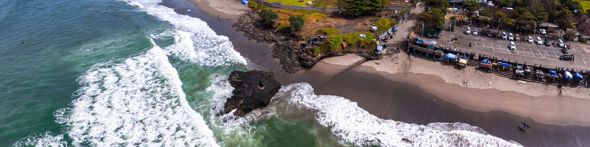 A coastal town with a beach, ocean waves, and a mix of residential and commercial buildings.