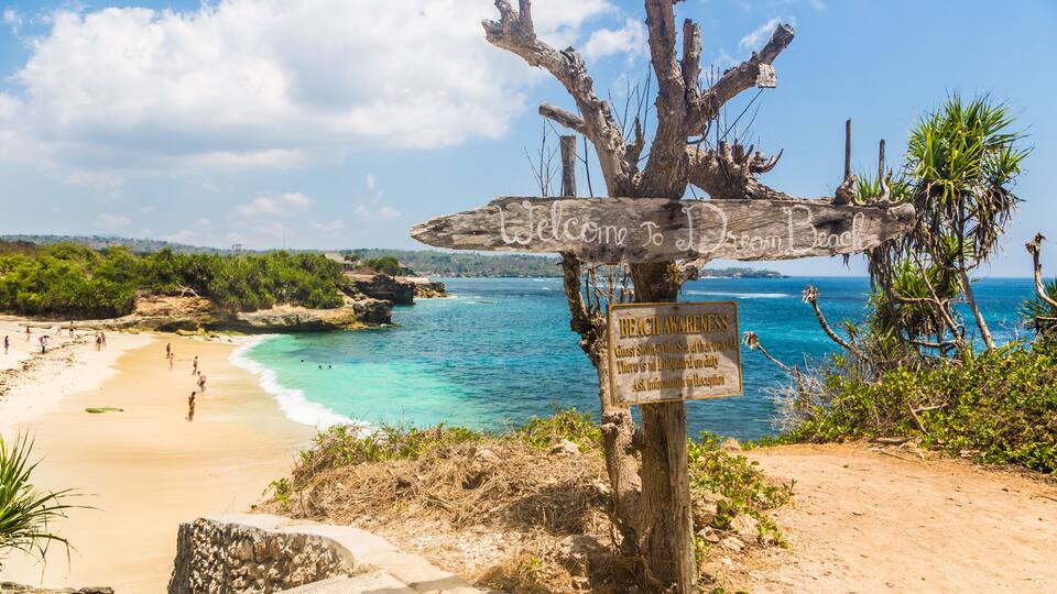 A beach with a wooden signpost and a beach awareness sign.