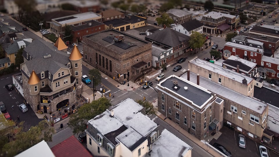 An aerial view of a historic town with distinct architectural styles, including a church with a golden dome and a large brick building with a flat roof.