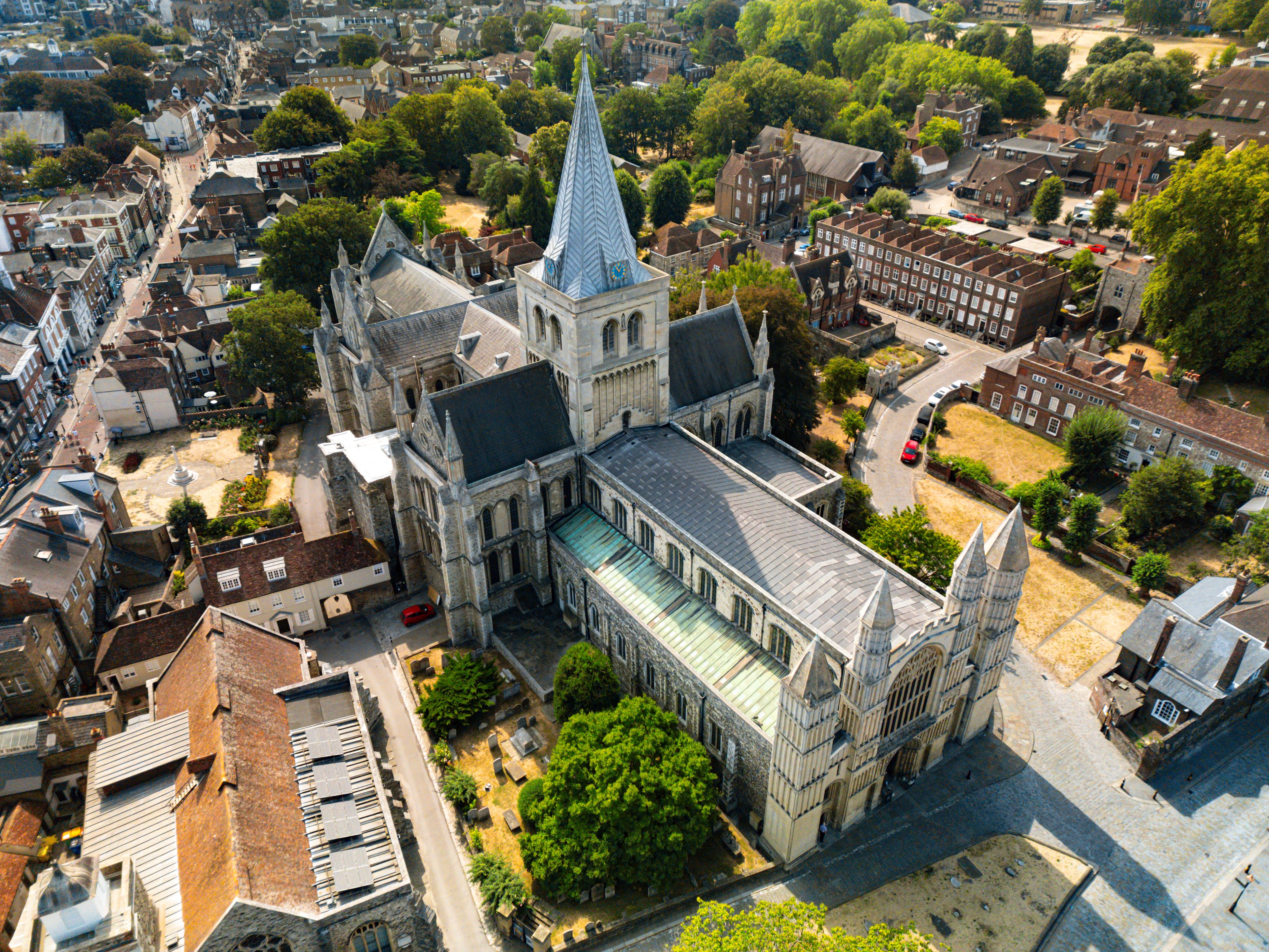 Uma catedral histórica com uma torre alta, rodeada por uma área urbana densa com ruas estreitas e edifícios tradicionais.