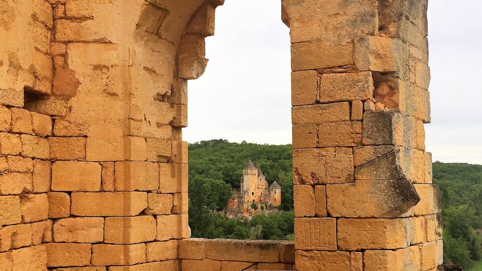 An ancient stone archway leading to a castle on a hill.