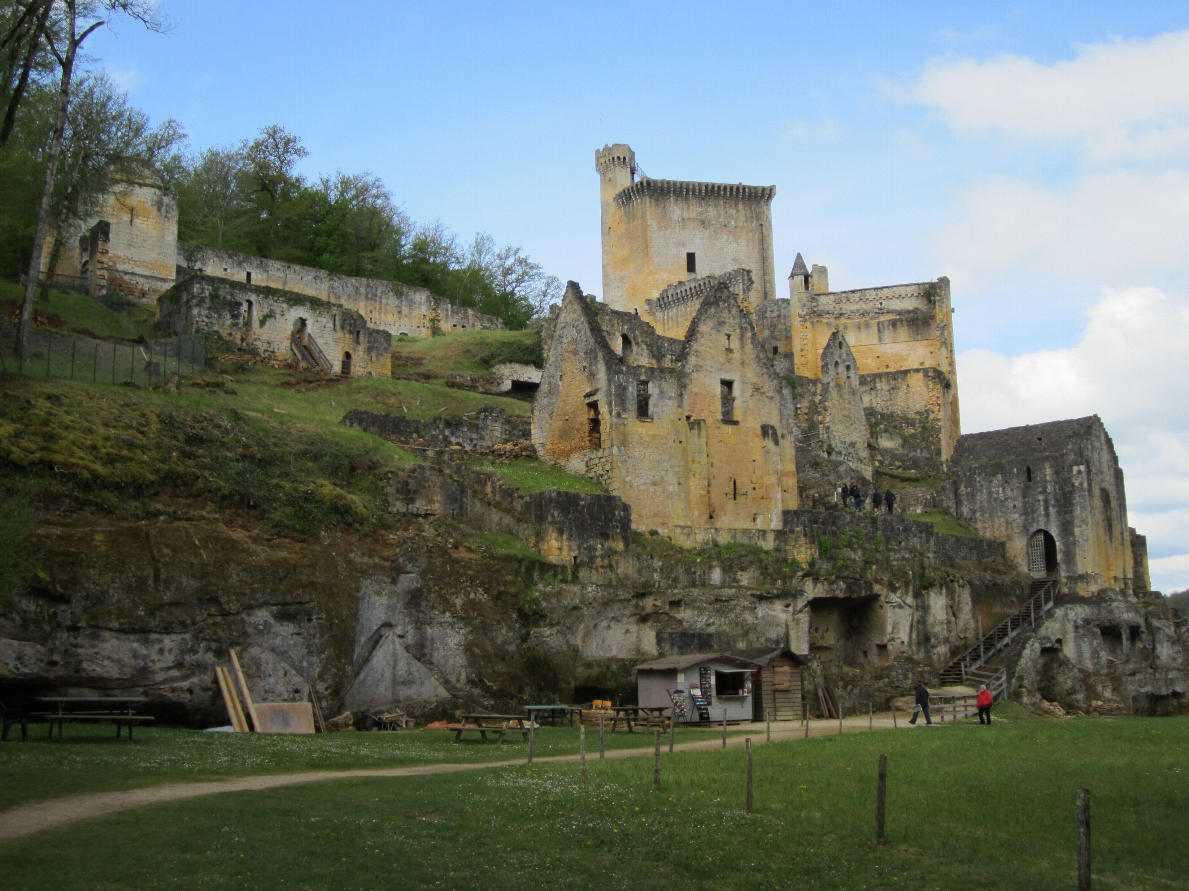 A historic castle with a prominent tower, situated on a grassy hill with a clear sky.