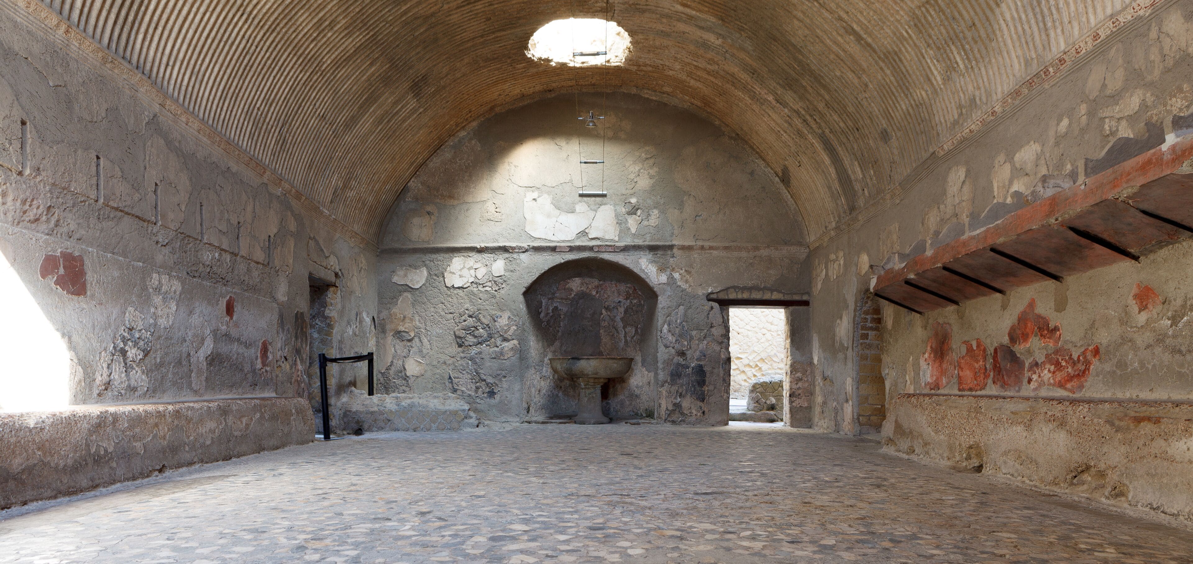 An ancient stone building with a vaulted ceiling, a large arched doorway, and a stone floor.