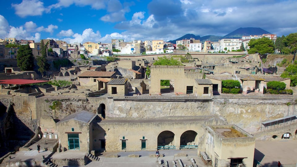 An ancient city with stone buildings, a prominent archway, and a mountain in the background.