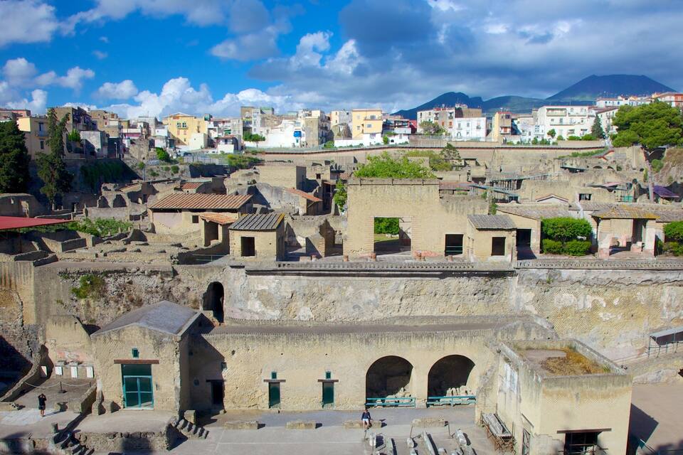An ancient city with stone buildings, a prominent archway, and a mountain in the background.