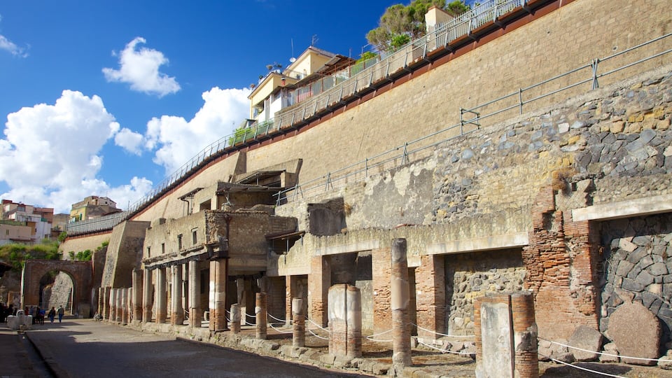 Ancient ruins with stone columns and a stone wall.
