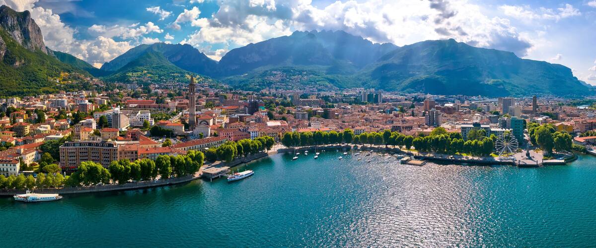 A coastal city with a river, a Ferris wheel, and mountains in the background.