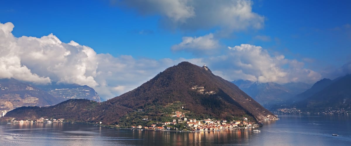 A mountainous landscape with a lake, a small town, and a prominent peak.