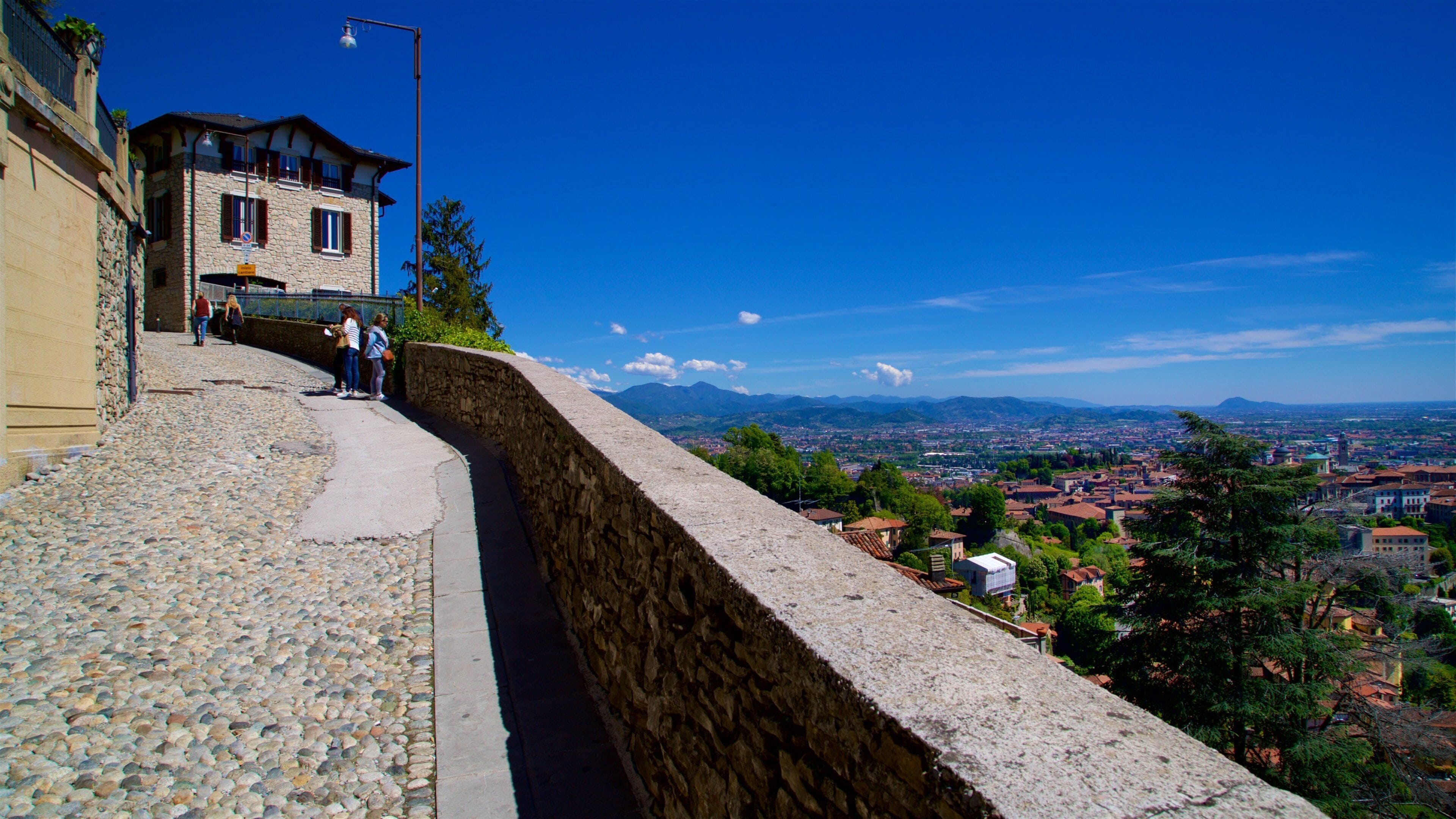 A stone wall with a view of a town and mountains in the distance.