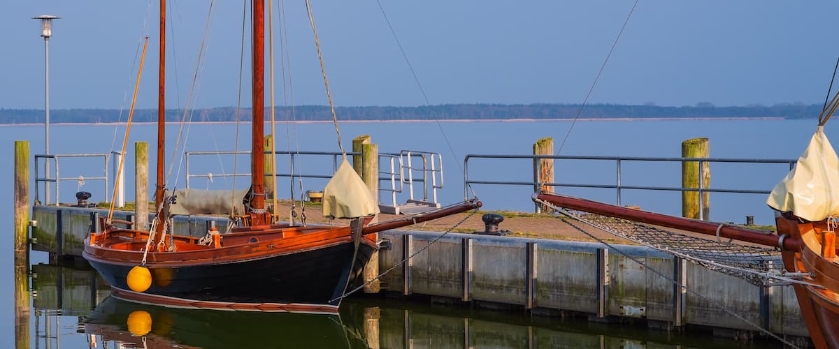 A dock with a boat, a wooden post, and a metal railing.