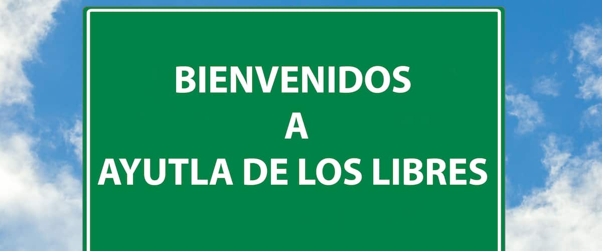 A green welcome sign with white text against a blue sky with clouds.