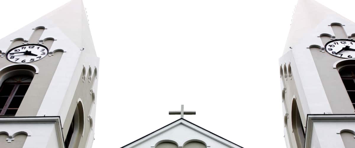 A church with two clock towers and a statue of a woman holding a child.