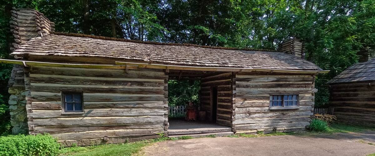 A rustic log cabin with a gravel driveway and a covered entrance.