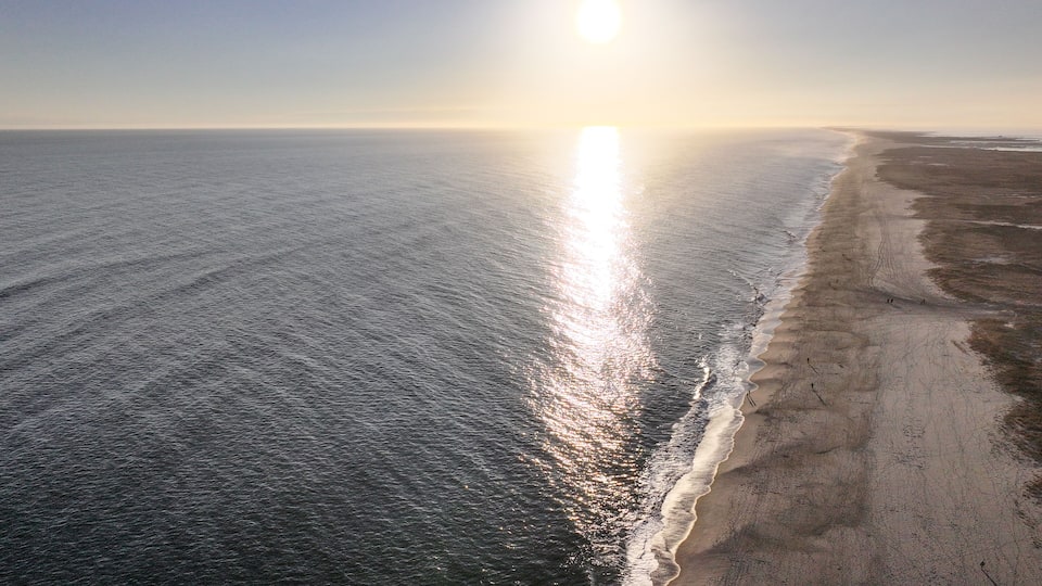 A beach with waves and a clear sky.