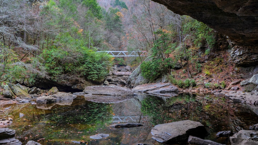 A metal bridge reflected in North Chickamauga Creek Gorge is part of the Cumberland Trail in Tennessee. View from an alcove at the creek crossing.