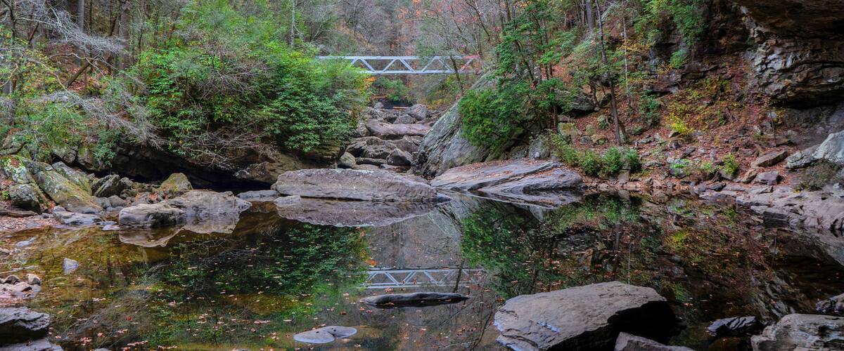 A metal bridge reflected in North Chickamauga Creek Gorge is part of the Cumberland Trail in Tennessee. View from an alcove at the creek crossing.