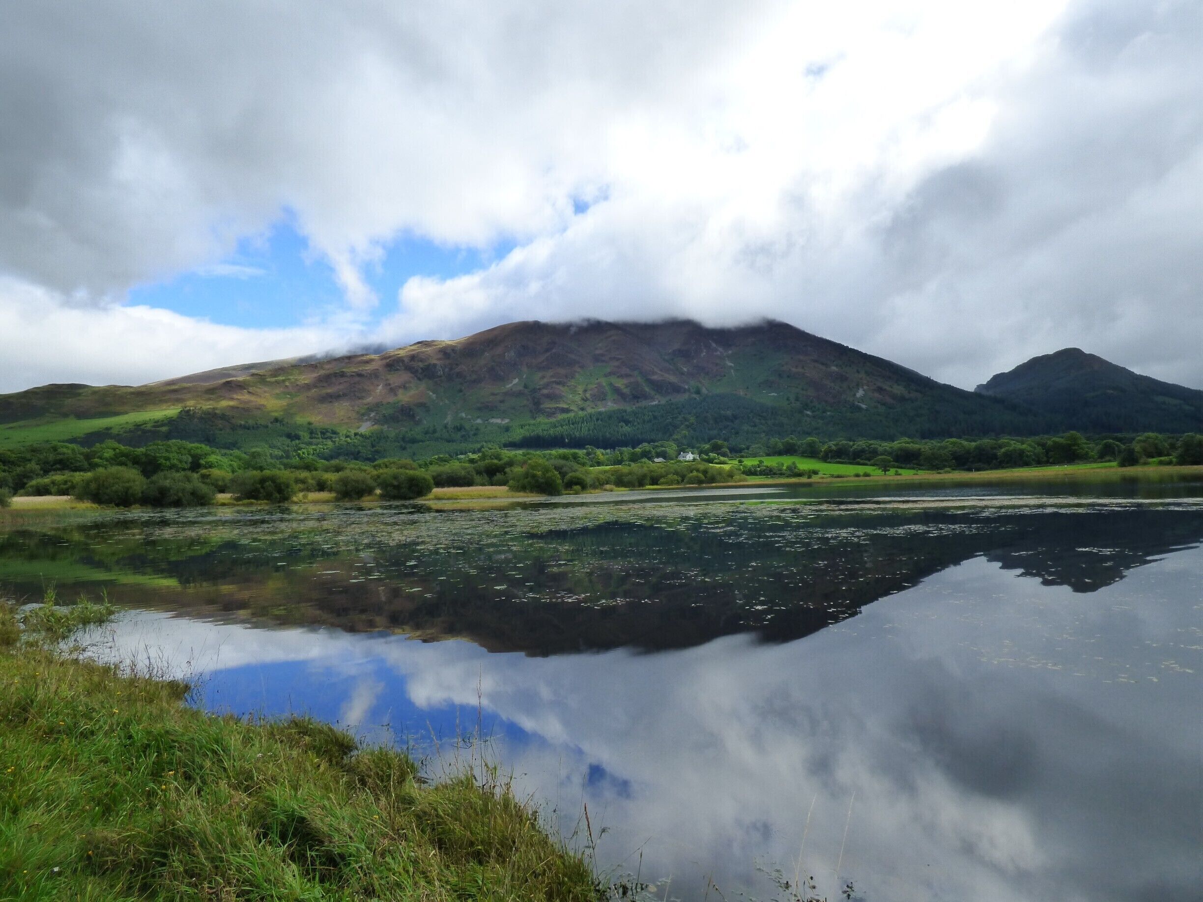 A lake reflecting a mountain and cloudy sky.