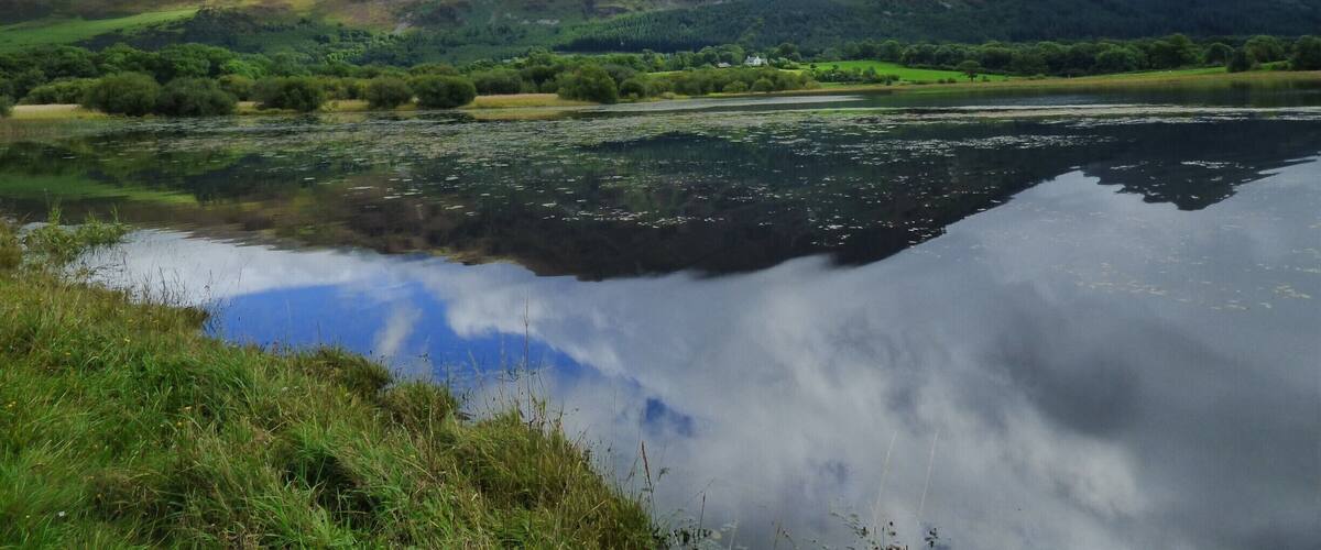 A lake reflecting a mountain and cloudy sky.