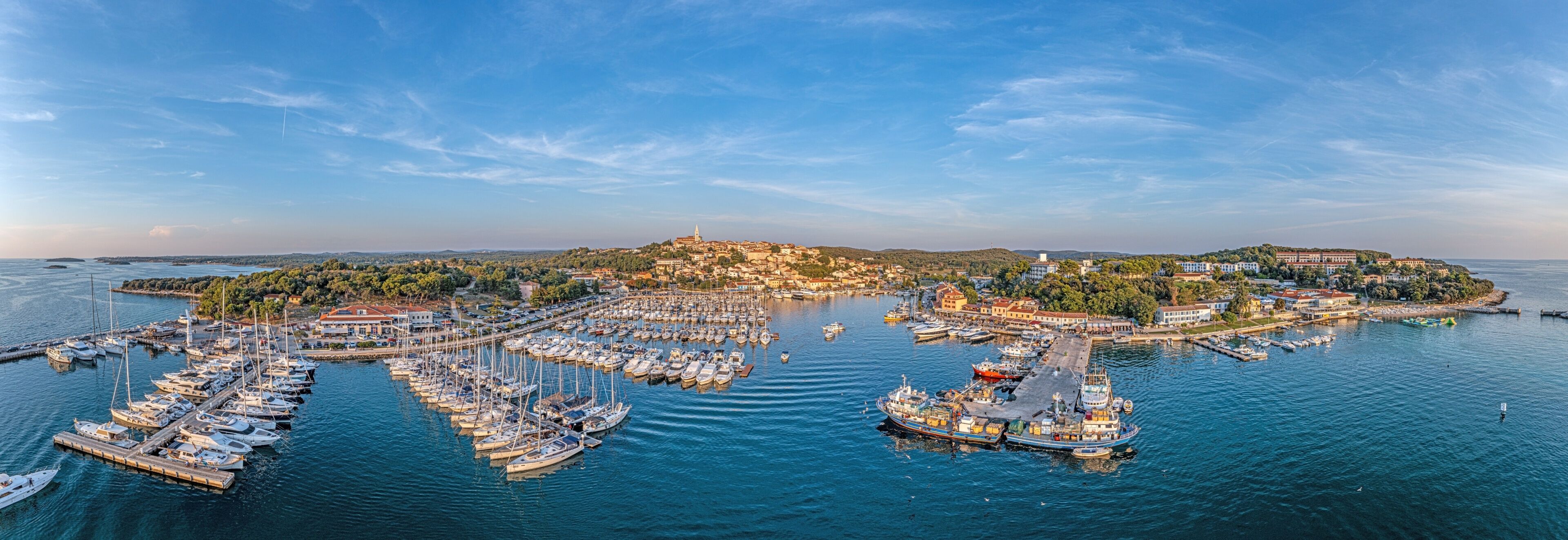 A coastal town with a marina, boats, and a hilltop church.