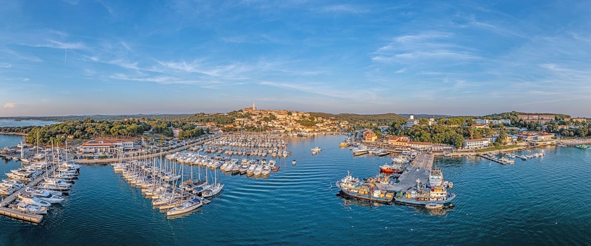 A coastal town with a marina, boats, and a hilltop church.