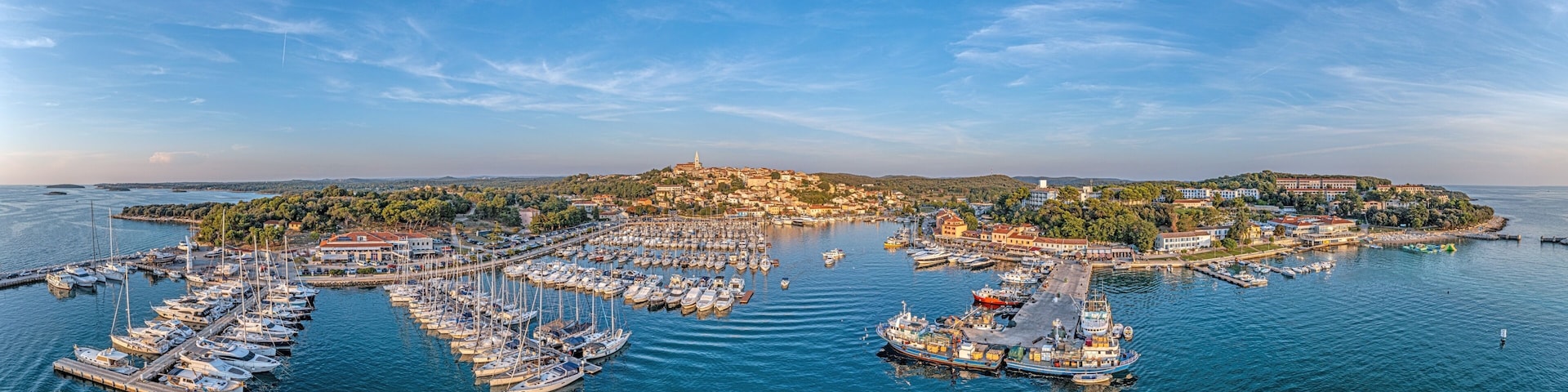 A coastal town with a marina, boats, and a hilltop church.