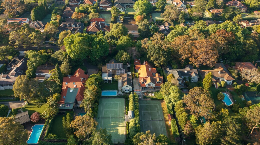 Aerial view of upmarket houses with private gardens, pools and tennis courts on Sydney's leafy North Shore.