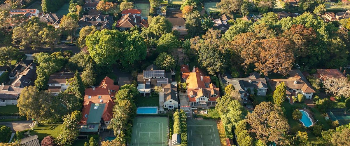 Aerial view of upmarket houses with private gardens, pools and tennis courts on Sydney's leafy North Shore.