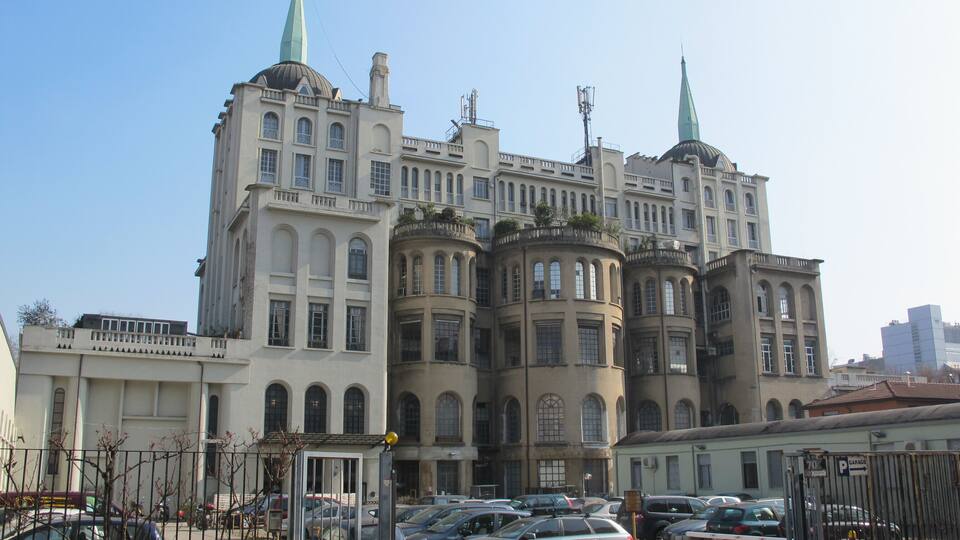 Ein historisches Gebäude mit mehreren Türmen und einem Parkplatz davor.